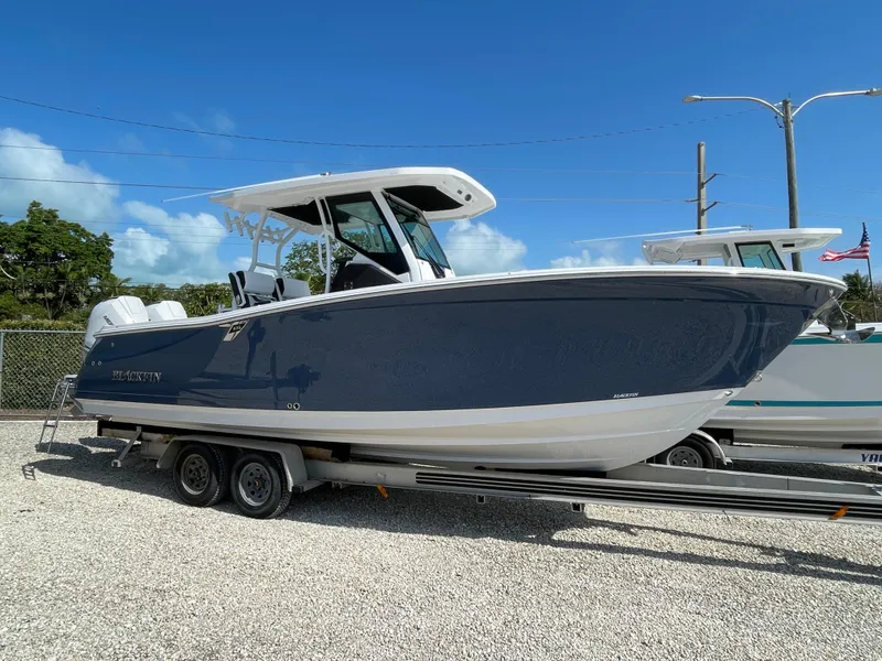 Slide: The Image of 2025 Blackfin 272CC boat on trailer under clear blue sky. - 43