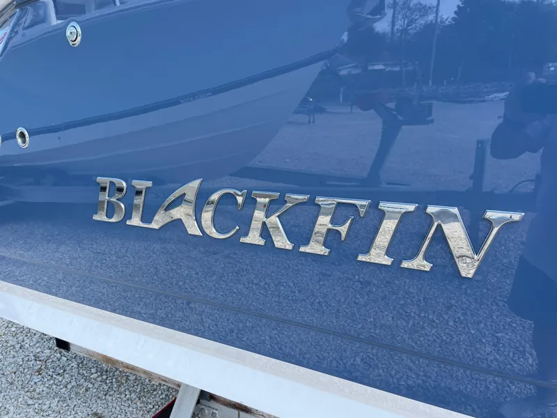 Slide: The Image of 2025 Blackfin 272CC boat logo on blue hull, close-up view. - 7