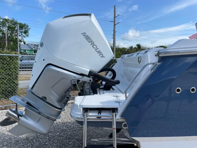 Slide: The Image of 2025 Blackfin 272CC boat with Mercury outboard motor, docked under a clear blue sky. - 9