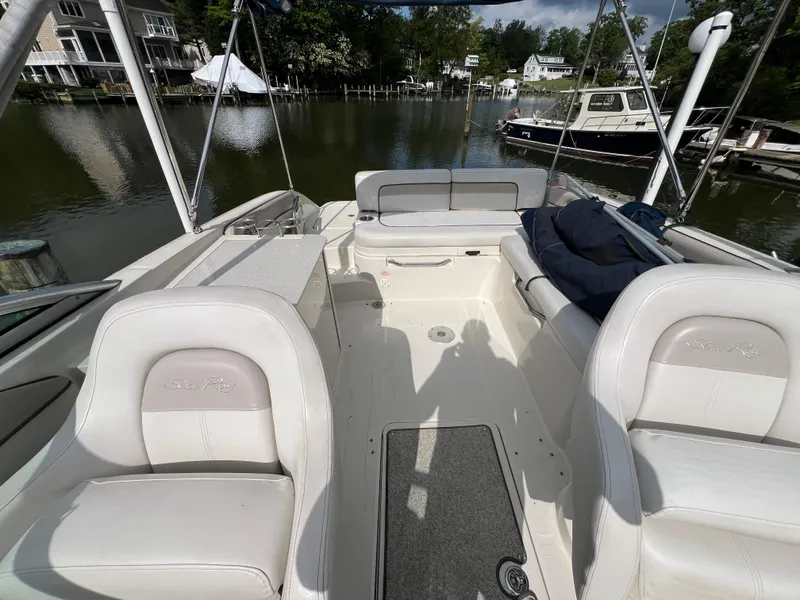 Slide: The Image of 2010 Sea Ray 280 Sundeck interior with white seating, docked near waterfront homes. - 13