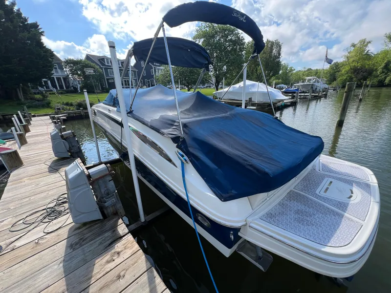 Slide: The Image of 2010 Sea Ray 280 Sundeck boat docked with blue cover, surrounded by water and greenery. - 24
