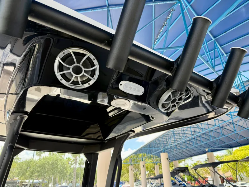 Slide: The Image of 2024 Yamaha Boats 255 FSH Sport H with speakers and rod holders under blue canopy. - 4