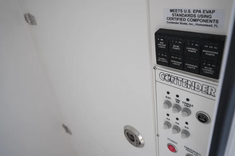 Slide: The Image of Control panel of 2025 Contender 25T boat, featuring switches and EPA compliance label. - 14