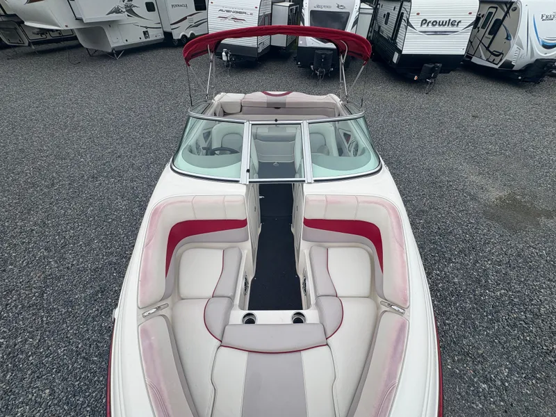Slide: The Image of 2012 Bryant 220 boat with red and white interior, parked near RVs. - 17