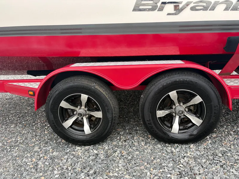 Slide: The Image of Red trailer with dual wheels for 2012 Bryant 220 boat on gravel surface. - 7