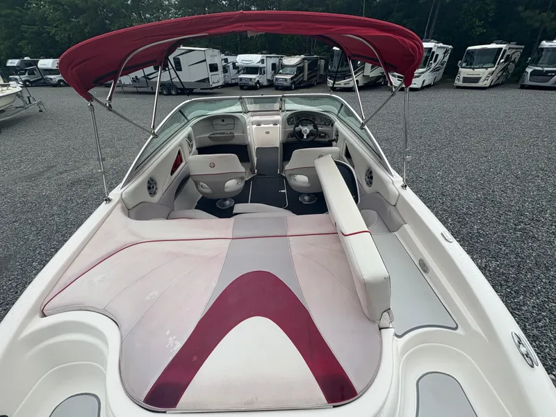 Slide: The Image of 2012 Bryant 220 boat with red canopy, spacious seating, and sleek design in a parking lot. - 9