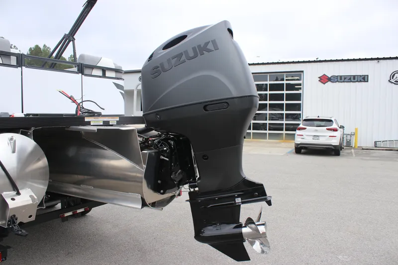 Slide: The Image of 2025 Avalon VENTURE QUAD LOUNGER with Suzuki outboard motor in dealership lot. - 12