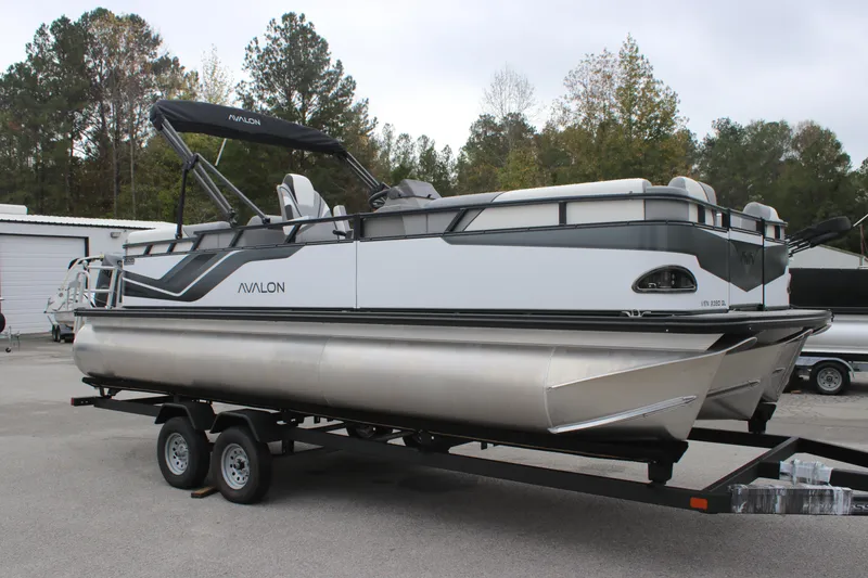 Slide: The Image of 2025 Avalon Venture Quad Lounger pontoon boat on trailer, parked outdoors. - 2