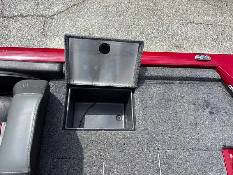 Slide: The Image of 2024 Tracker Pro Team 190 TX boat storage compartment with open lid on carpeted deck. - 22