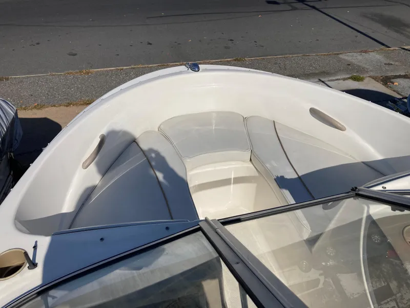 Slide: The Image of 2003 Bayliner 180 Bowrider boat interior with seating and windshield, parked on pavement. - 7