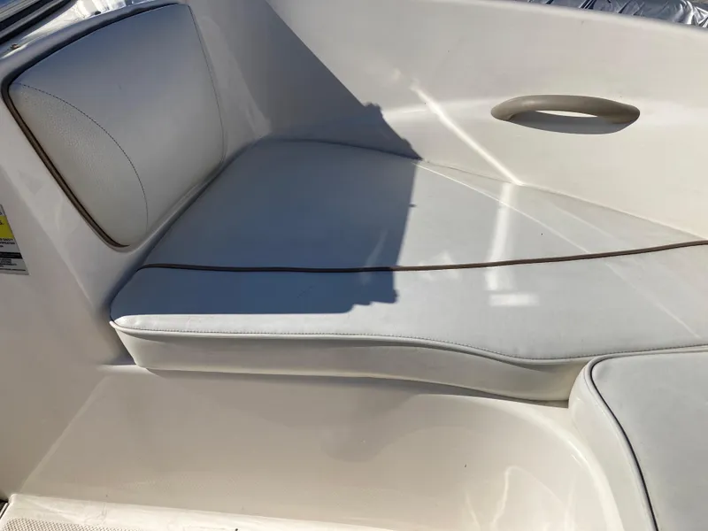 Slide: The Image of 2003 Bayliner 180 Bowrider interior seating with white upholstery and sleek design. - 8