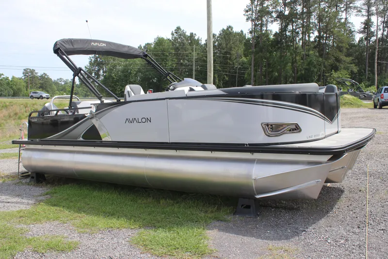 The Image of 2025 Avalon LSZ Versatile Rear Lounger pontoon boat parked on gravel. - 0