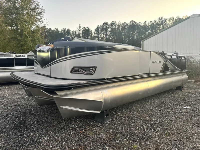Slide: The Image of 2025 Avalon LSZ Versatile Rear Lounger pontoon boat on gravel lot, side view. - 8