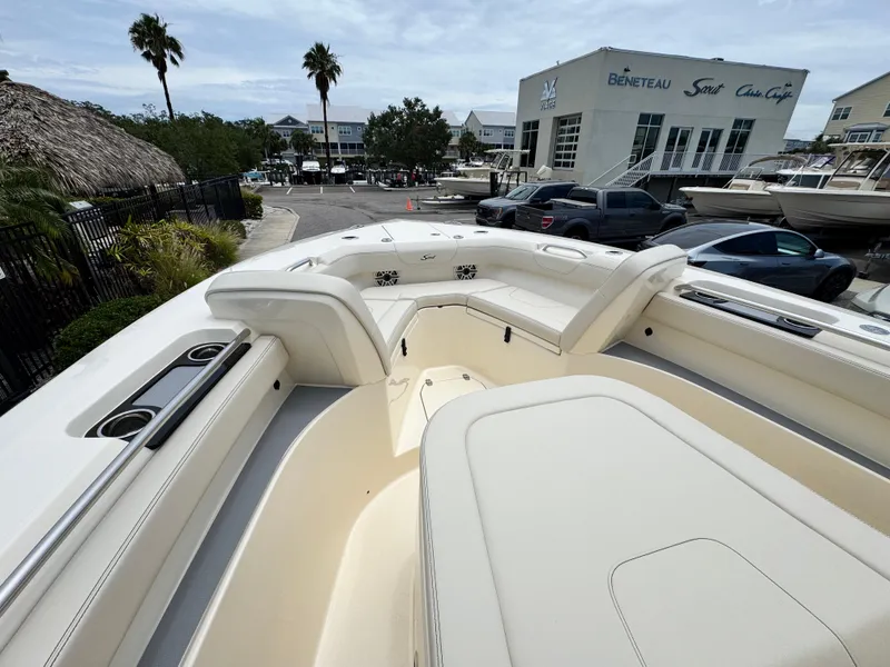 Slide: The Image of 2025 Scout 305 LXF boat interior with seating, docked near a dealership. - 13