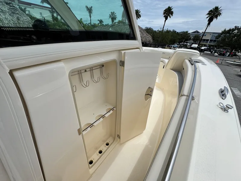 Slide: The Image of 2025 Scout 305 LXF boat storage compartment with open door, showcasing hooks and shelves. - 21
