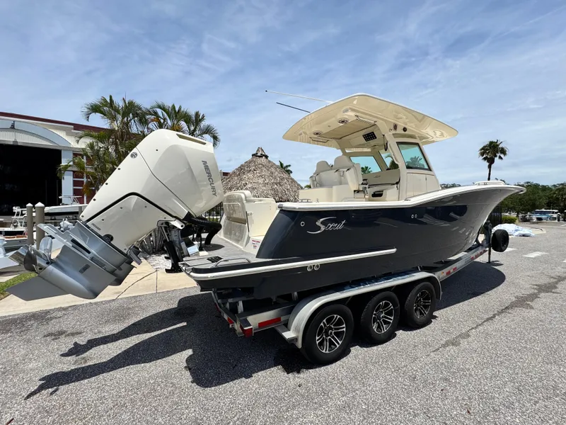 Slide: The Image of 2025 Scout 305 LXF boat on trailer, parked outdoors, featuring dual outboard engines. - 3