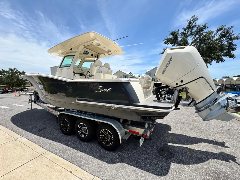 Slide: The Image of 2025 Scout 305 LXF boat on trailer with Mercury outboard, parked outdoors. - 4