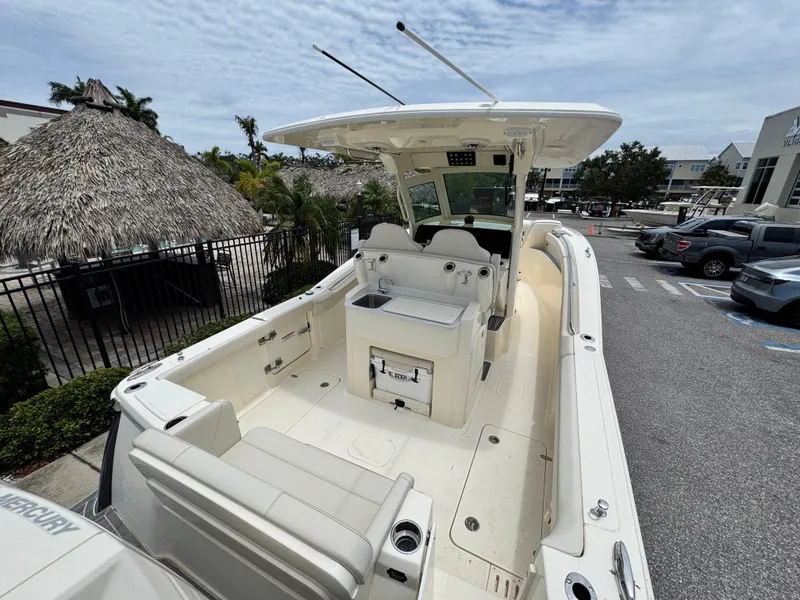 Slide: The Image of 2025 Scout 305 LXF boat with spacious deck and seating, parked outdoors. - 6