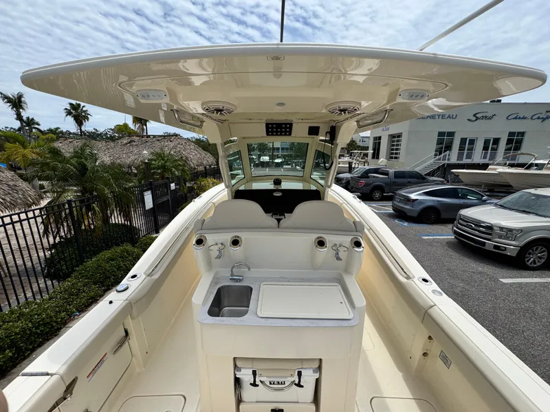 Slide: The Image of 2025 Scout 305 LXF boat interior with helm, sink, and storage, parked at a marina. - 8