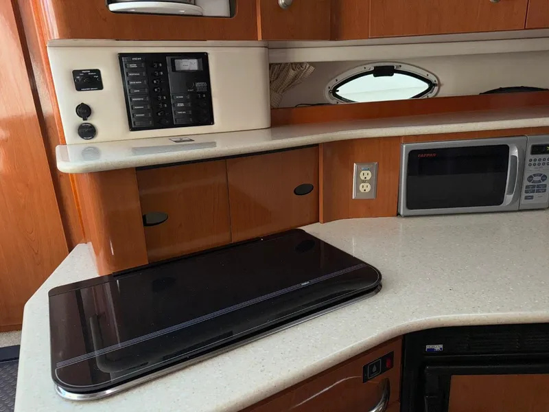 Slide: The Image of 2006 Maxum 3300 SE yacht interior kitchen with stove, microwave, and wooden cabinetry. - 10