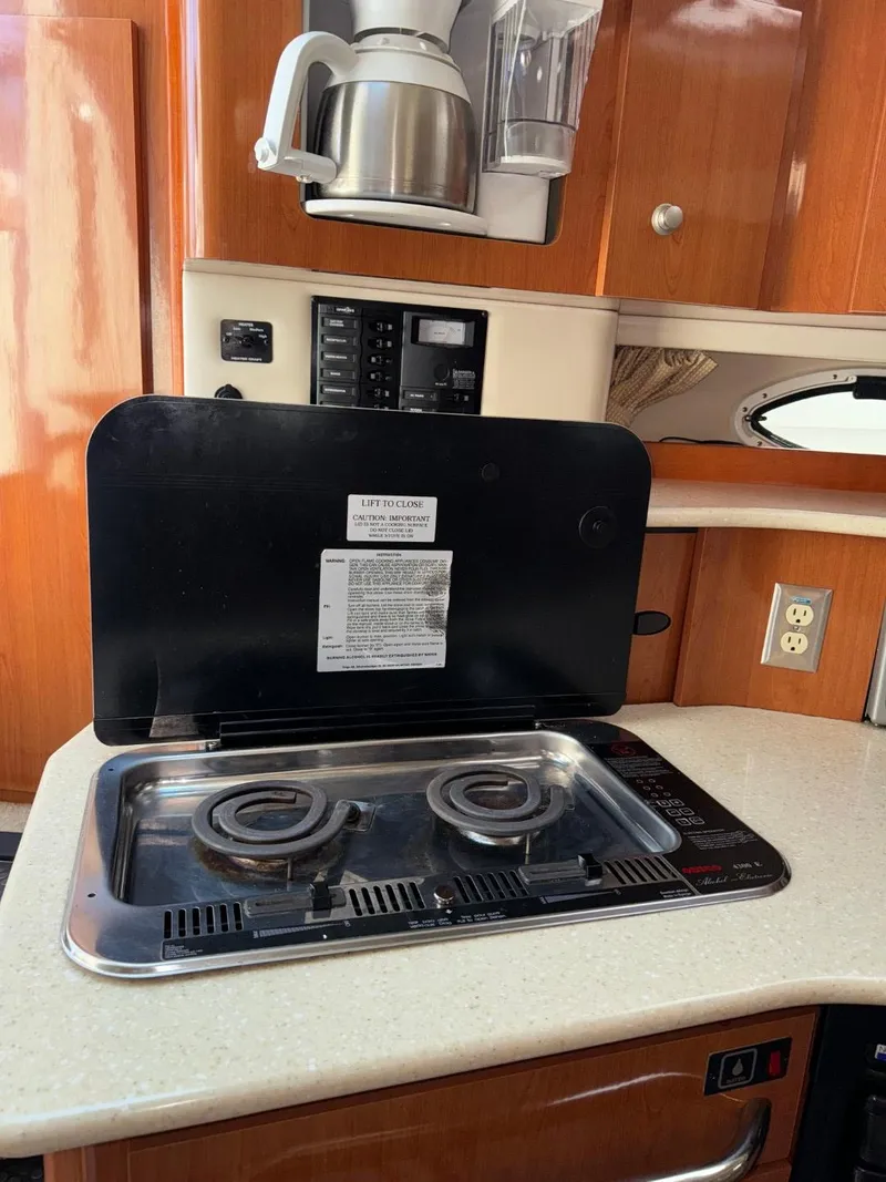 Slide: The Image of 2006 Maxum 3300 SE yacht kitchen with electric stove and wooden cabinetry. - 11