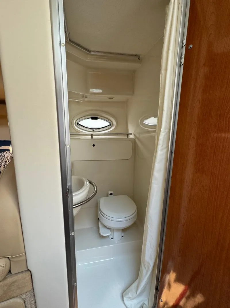 Slide: The Image of 2006 Maxum 3300 SE boat bathroom with toilet, sink, and porthole window. - 15