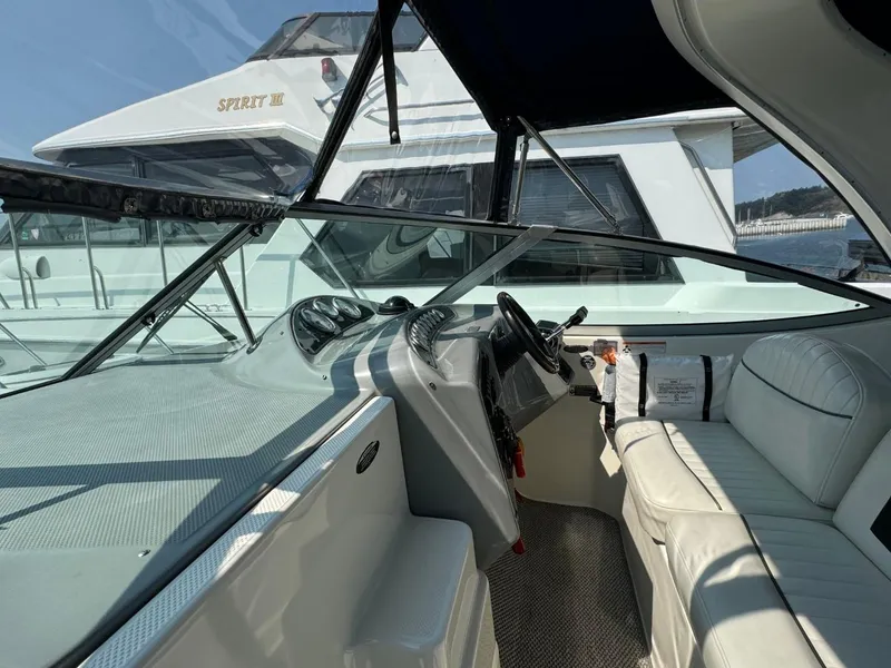 Slide: The Image of 2006 Maxum 3300 SE boat interior with white seating and steering wheel, docked near another vessel. - 17