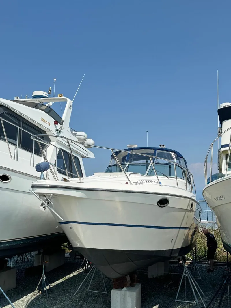 Slide: The Image of 2006 Maxum 3300 SE boat on stands, flanked by other vessels, under clear blue sky. - 2