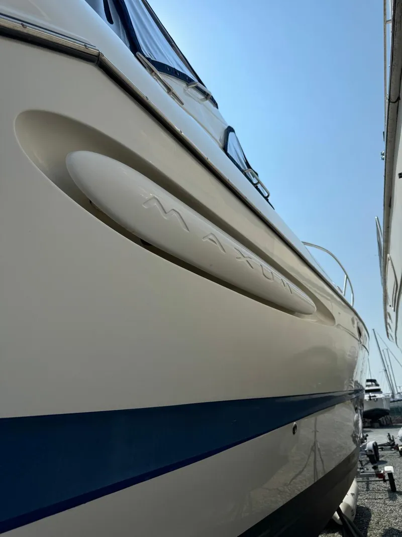 Slide: The Image of 2006 Maxum 3300 SE boat side view with blue stripe under clear sky. - 29