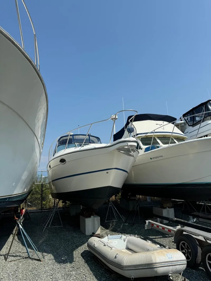 Slide: The Image of 2006 Maxum 3300 SE boat on dry dock, surrounded by other vessels under clear blue sky. - 3