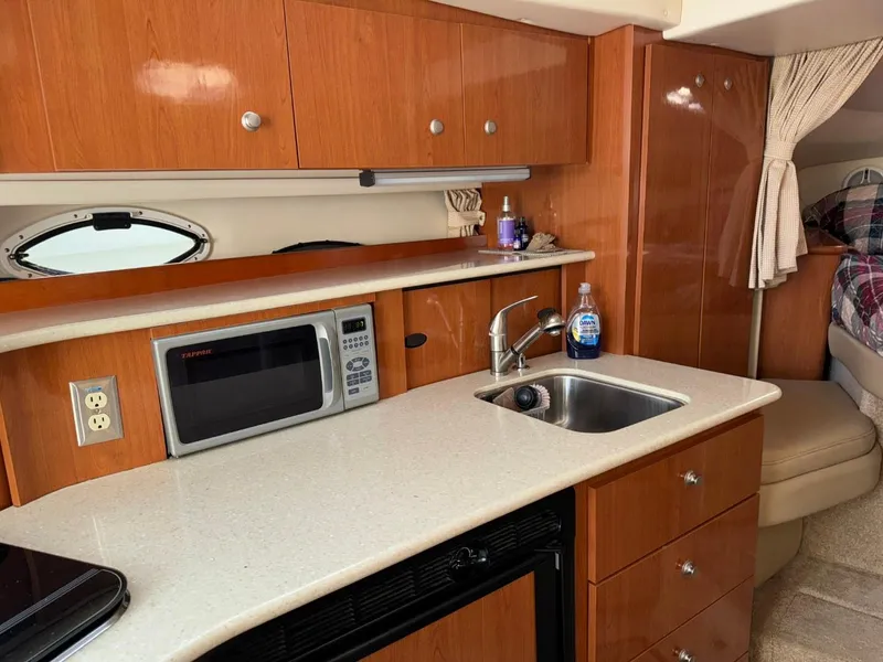 Slide: The Image of 2006 Maxum 3300 SE yacht interior with kitchenette, microwave, sink, and wood cabinetry. - 8