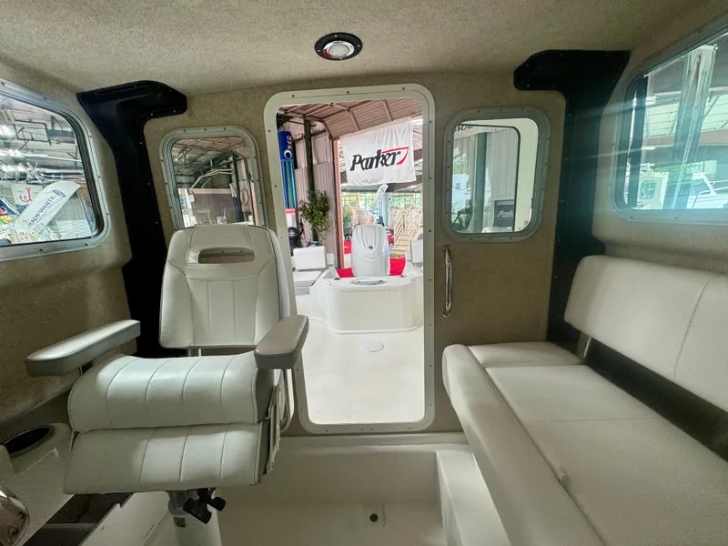 Slide: The Image of Interior of 2025 Parker 2120 Sport Cabin boat with white seating and windows. - 11