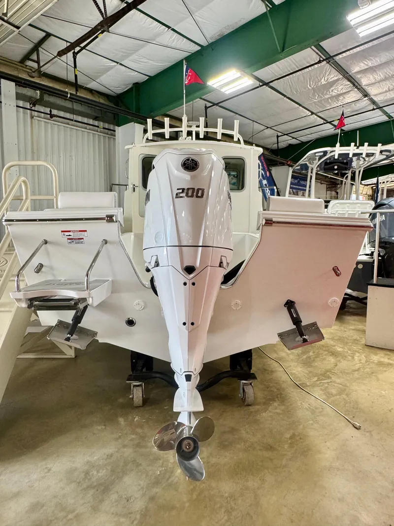 Slide: The Image of 2025 Parker 2120 Sport Cabin boat with 200 HP outboard motor in a showroom. - 3