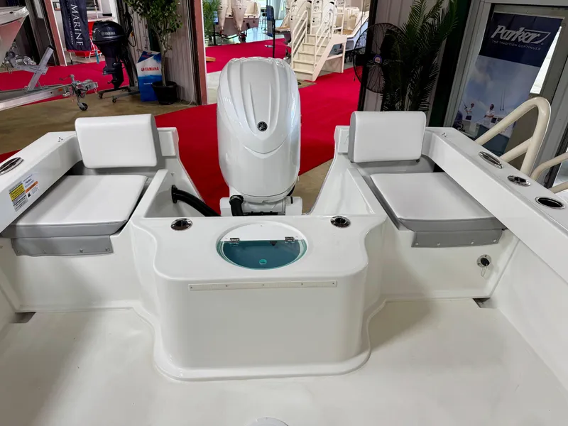 Slide: The Image of 2025 Parker 2120 Sport Cabin boat interior with seating and motor, displayed at a boat show. - 5