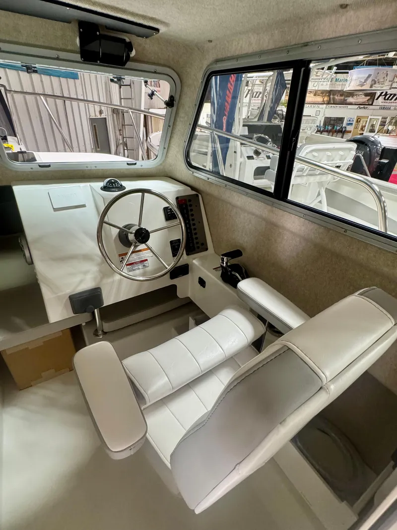 Slide: The Image of Interior of 2025 Parker 2120 Sport Cabin boat with steering wheel and seating. - 8