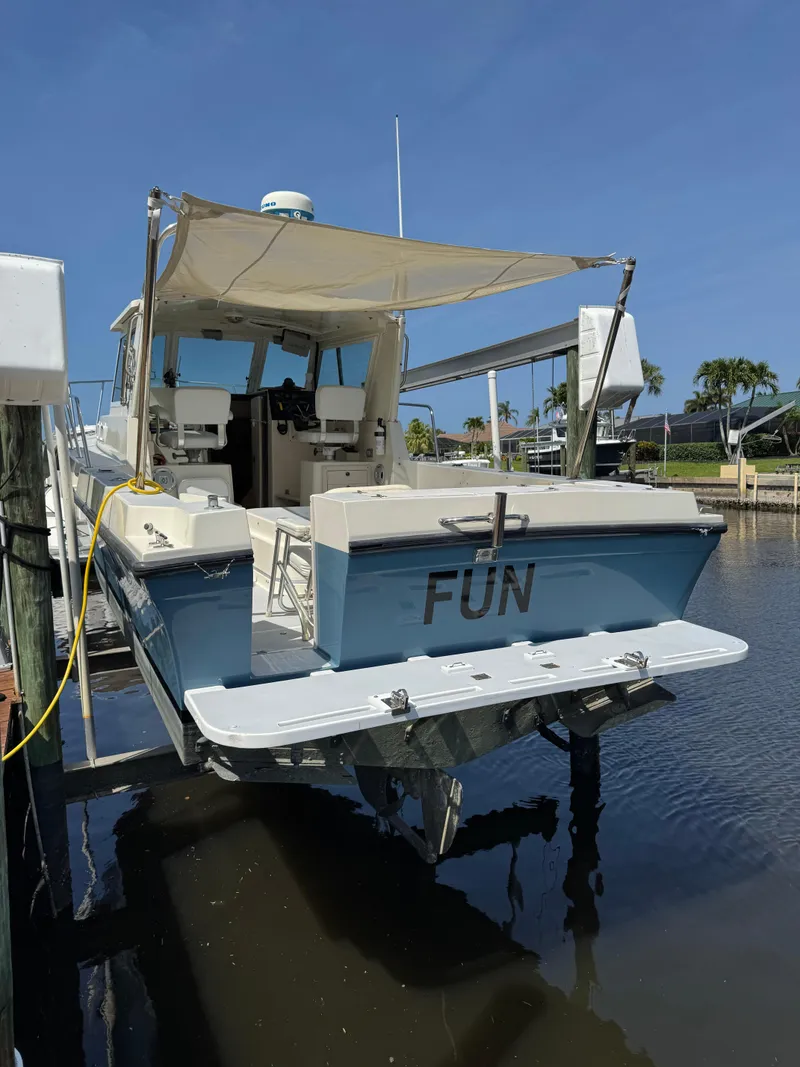 Slide: The Image of 1996 Albin Tournament Express boat docked, featuring a canopy and "FUN" on the stern. - 1