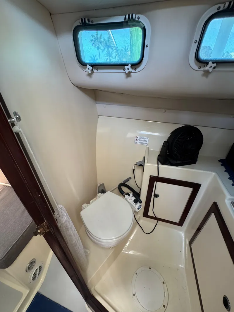 Slide: The Image of 1996 Albin Tournament Express boat bathroom with toilet, storage cabinet, and porthole windows. - 20