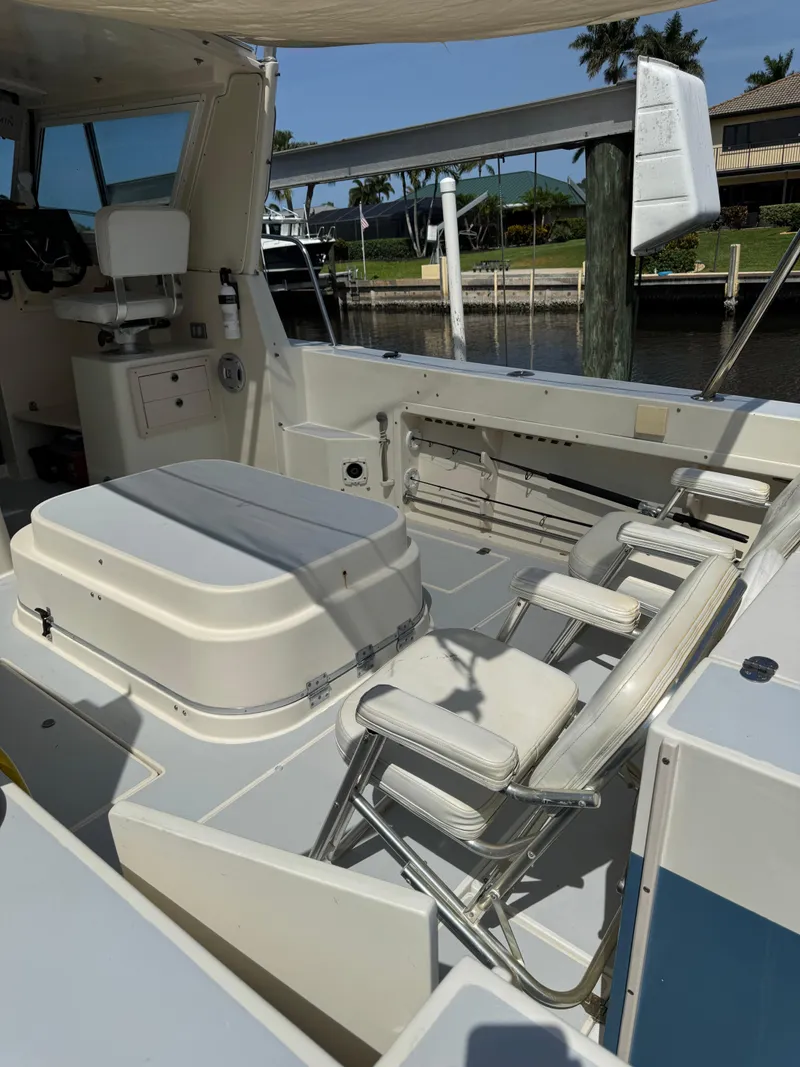 Slide: The Image of 1996 Albin Tournament Express boat interior with seating and storage, docked by a waterfront. - 4