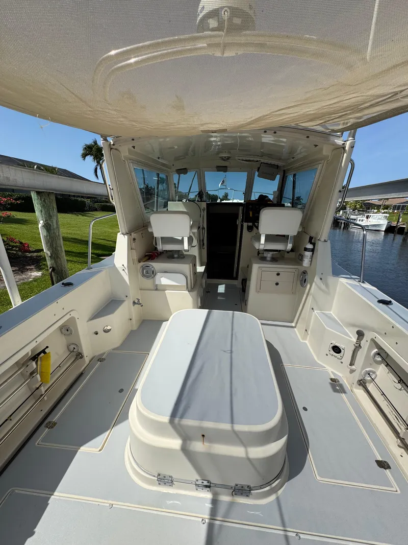 Slide: The Image of 1996 Albin Tournament Express boat interior with seating and helm, docked by a scenic waterfront. - 6