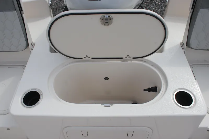 Slide: The Image of 2024 Carolina Skiff 21 LS boat storage compartment with open lid and cup holders. - 15