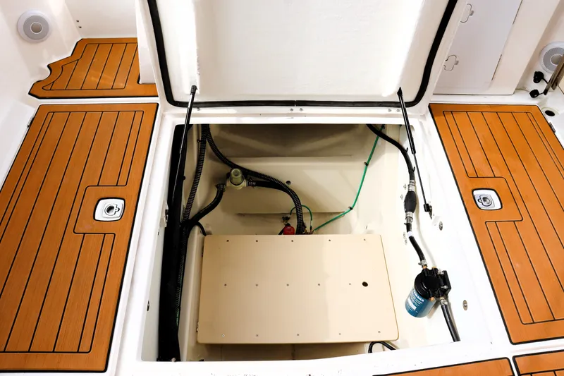 Slide: The Image of 2022 Ranger Tugs R-25 boat storage compartment with open hatch and visible wiring. - 18