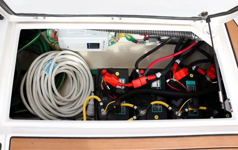 Slide: The Image of 2022 Ranger Tugs R-25 battery compartment with cables and coiled hose. - 19