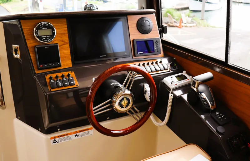 Slide: The Image of 2022 Ranger Tugs R-25 helm with wooden steering wheel and modern navigation controls. - 23