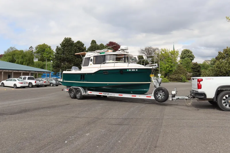 Slide: The Image of 2022 Ranger Tugs R-25 boat on trailer, parked in a lot, attached to a white truck. - 9