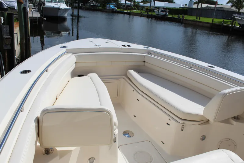 Slide: The Image of 2018 Grady-White Canyon 306 boat interior with white seating, docked by a calm waterway. - 11