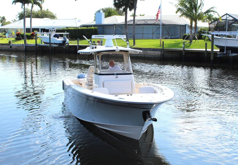 Slide: The Image of 2018 Grady-White Canyon 306 boat cruising on a calm canal near waterfront homes. - 2