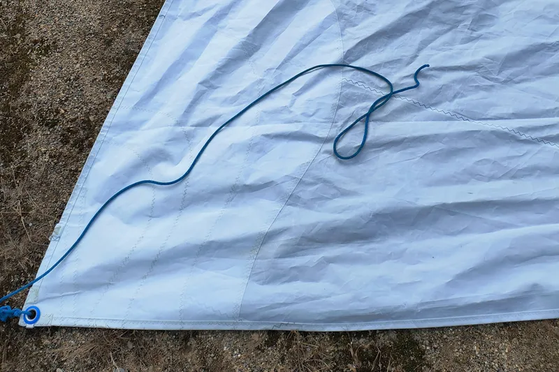 Slide: The Image of Close-up of a 2008 Hunter 216 sail with blue rope on sandy ground. - 17
