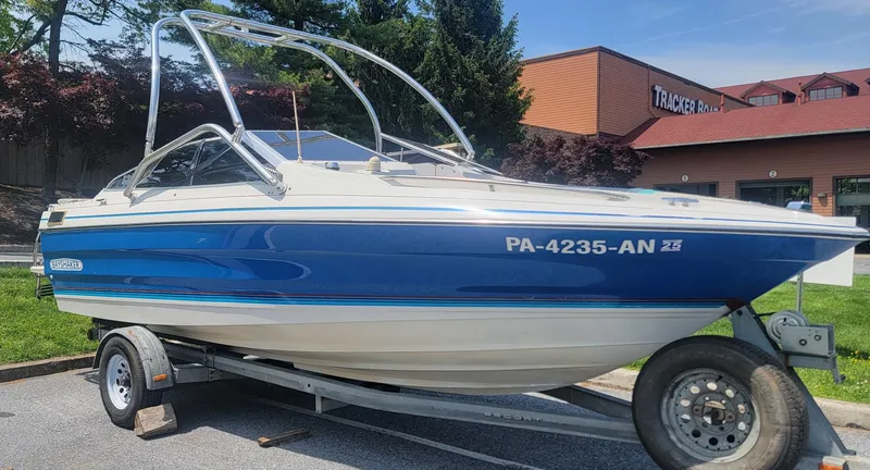Slide: The Image of 1988 Bayliner 2150 Capri boat on trailer, blue and white, parked outdoors. - 0