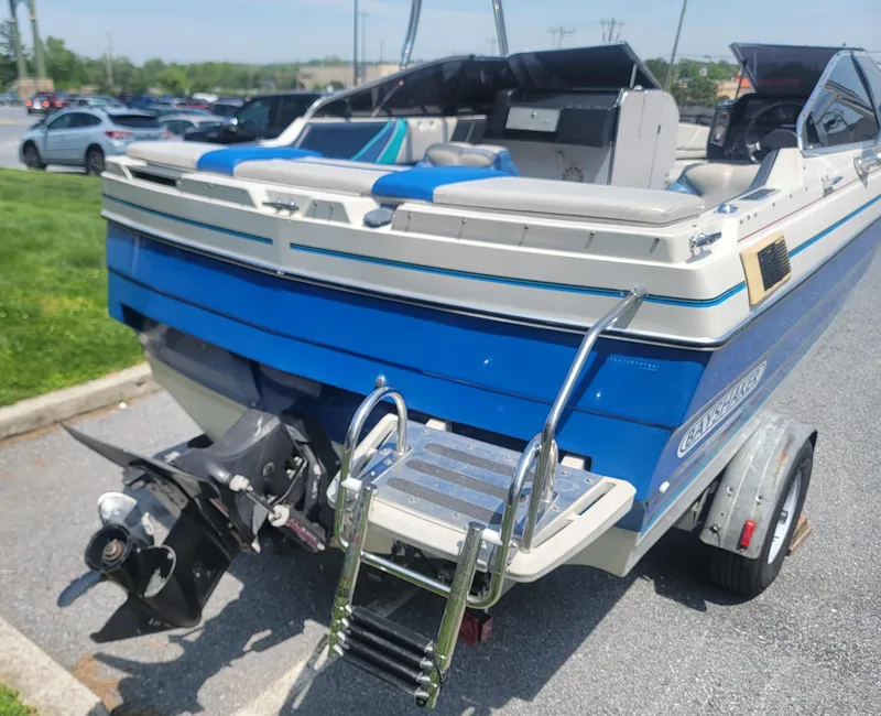 Slide: The Image of 1988 Bayliner 2150 Capri boat on trailer, featuring blue and white design with ladder. - 4