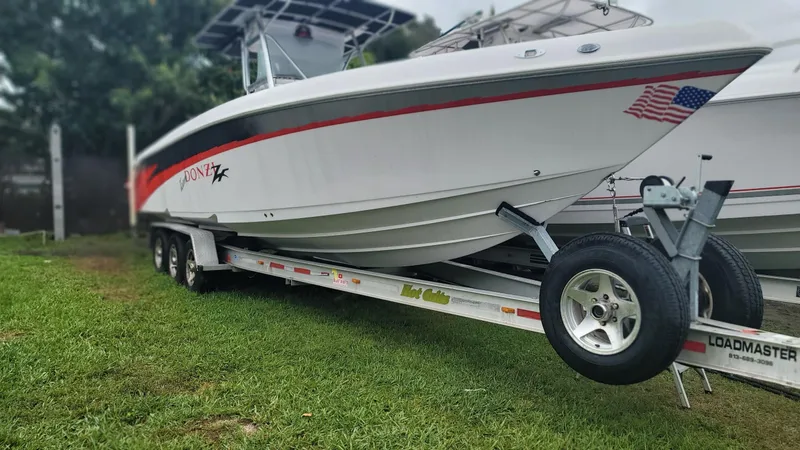 Slide: The Image of 2006 Donzi 32 ZF boat on trailer, white with red accents, parked on grass. - 14